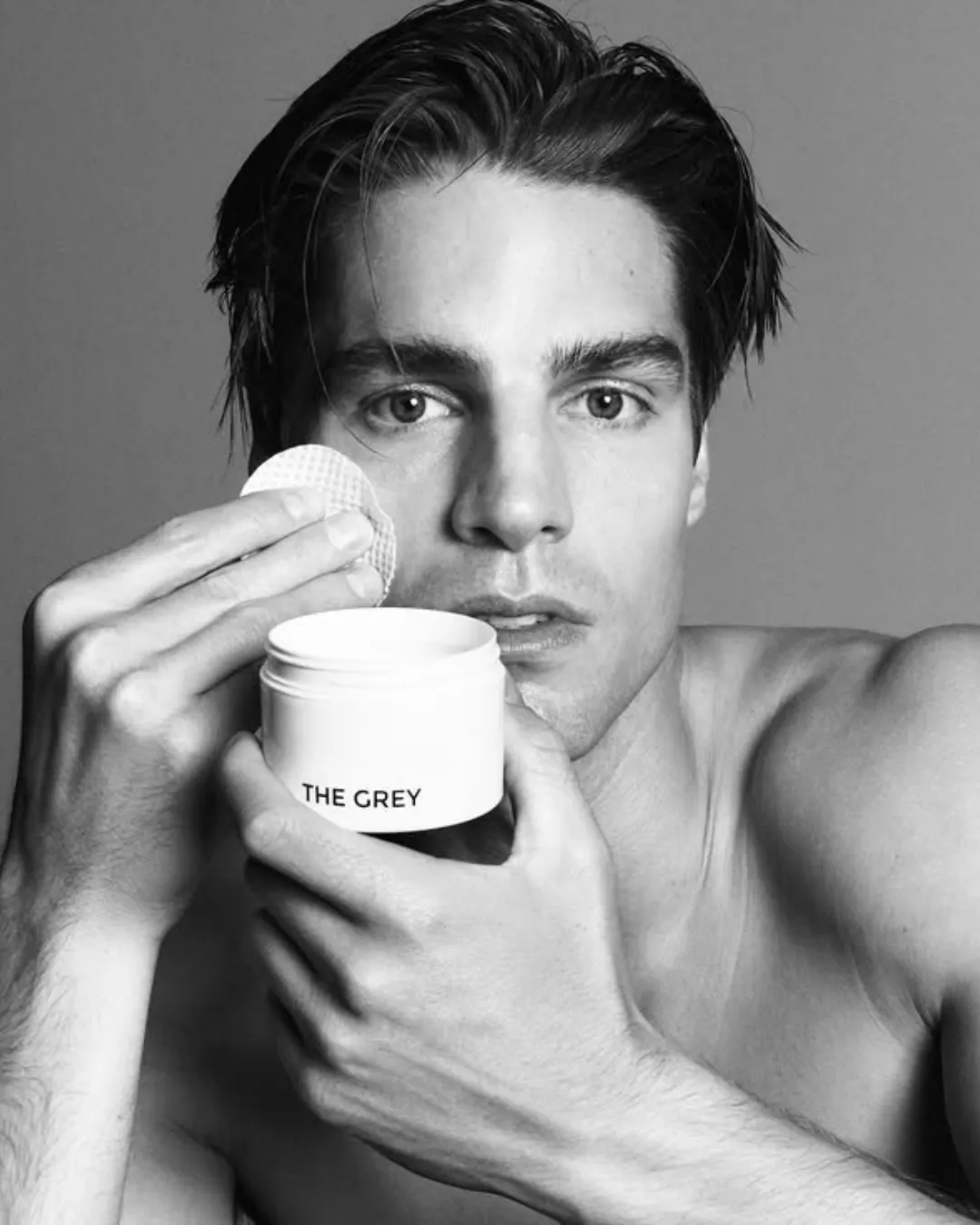 A man holding a jar of The Grey cream, men's grooming