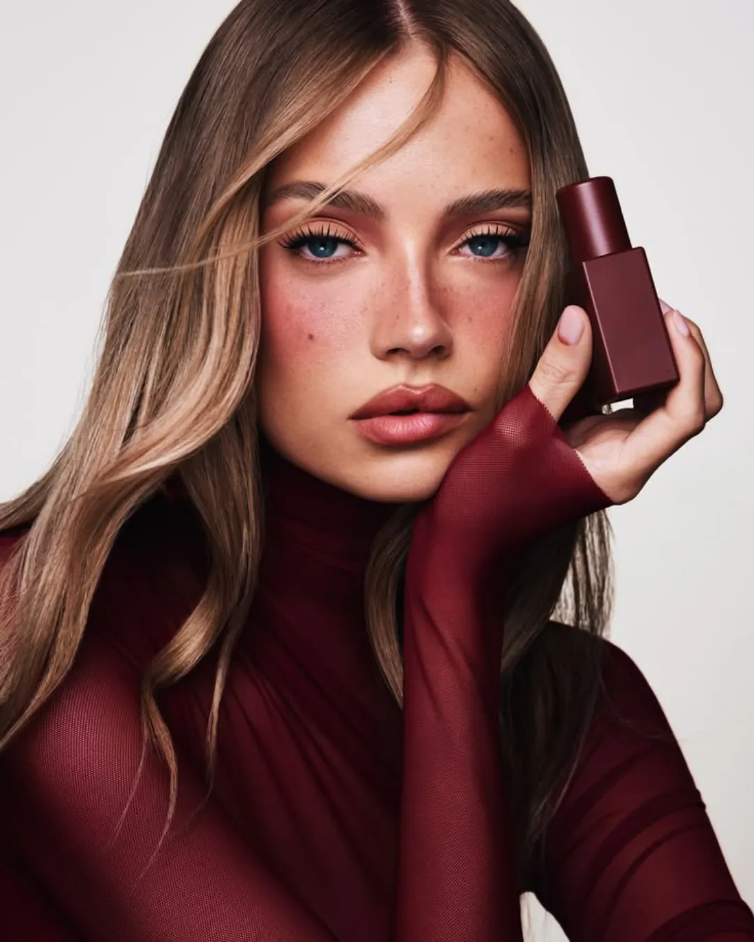 A model holding an oxblood bottle, growing a beauty brand